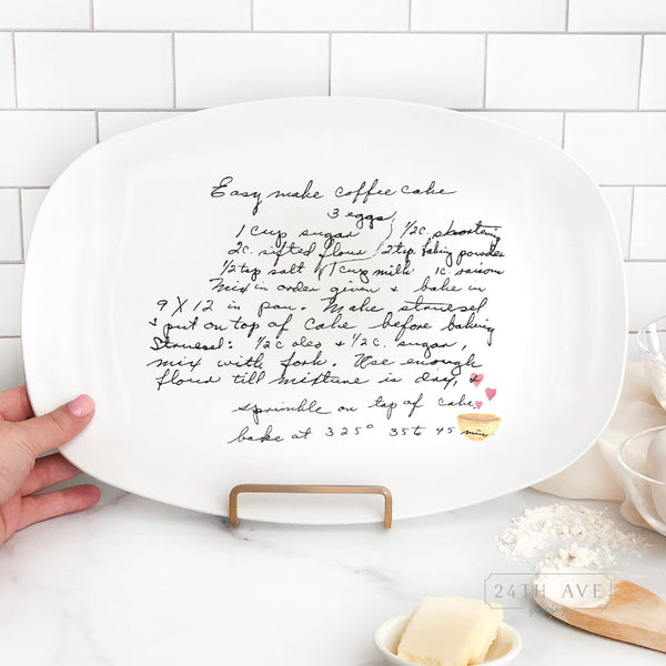Personalized handwritten recipe platter displayed on stand featuring original family recipe and heart bowl accent.